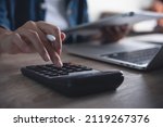 Business woman using calculator to calculate financial report, working at office with laptop computer on table. Asian female accountant or banker making calculations. finances and economy concept