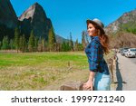 A young female tourist in a hat enjoys mountain views in Yosemite National Park