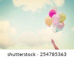 Girl hand holding multicolored balloons done with a retro vintage instagram filter effect, concept of happy birth day in summer and wedding honeymoon party (Vintage color tone)