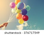 Girl hand holding multicolor balloons done with a retro instagram filter effect, concept of happy birth day in summer and wedding honeymoon party (Vintage color tone)