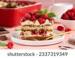 A piece of tiramisu with raspberries on a white plate on the table. Traditional Italian dessert. Selective focus