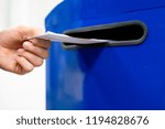Small photo of close up hand drop letter and documents in the blue postbox in post office mail