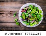 Fresh salad with mixed greens in bowl on wooden background
