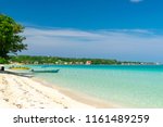 Sunny day along the Seven Mile Beach in tropical Negril, Jamaica. Tour boats await passengers and caucasian tourists in the water at a distance. Caribbean Jamaican summer beach vacation.