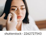 Small photo of Portrait of young Caucasian woman getting botox cosmetic injection in forehead. Beautiful woman gets botox injection in her face.