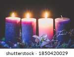 pink and purple candles in advent wreath decoration on black background