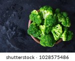 Fresh raw broccoli in a wooden bowl on a dark background