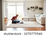 Small photo of Father playing ukulele with young son in their sitting room