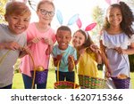 Portrait Of Five Children Wearing Bunny Ears On Easter Egg Hunt In Garden