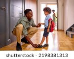 Parents At Home Helping Son Getting Ready To Go To School Putting On Shoes