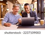 Small photo of Mature Businessman Mentoring Younger Colleague Working On Laptop At Desk