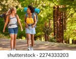 Two Female Friends With Backpacks On Vacation Hiking Through Countryside Together