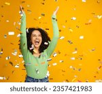Small photo of Studio Shot Of Excited Woman Celebrating Big Win Showered In Tinsel Confetti On Yellow Background