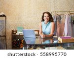 Young woman working in clothes shop leaning on counter