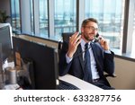 Businessman Making Phone Call Sitting At Desk In Office