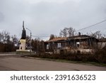 Small photo of 11-09-2023 Murom Russia. Russia's contrasts - militant militarism and abject poverty: fairy tale hero Ilya Muromets and wooden house with gaping window and boarde up window. and statue of Warrior