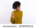 No sign gesture. Closeup portrait unhappy Young beautiful African American woman wearing knitted sweater against white wall raising fore finger up saying no. Negative emotions facial expressions, feel