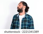 Small photo of young bearded hispanic man wearing plaid shirt over white background with snobbish expression curving lips and raising eyebrows, looking with doubtful and skeptical expression, suspect and doubt.