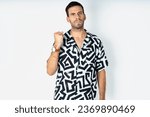 Small photo of young handsome businessman wearing printed shirt shows fist has annoyed face expression going to revenge or threaten someone makes serious look. I will show you who is boss
