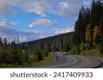 Small photo of Zakarpattia Oblast, Ukraine - October 29, 2020: The car moves along a winding asphalt road among the mountains. All around are autumn trees, yellowed and reddened leaves combined with green needles.