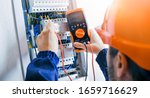 Small photo of Electrician installing electric cable wires and fuse switch box. Multimeter in hands of electricians detail.