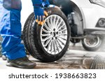 Small photo of Car mechanic working in garage and changing wheel alloy tire. Repair or maintenance auto service.