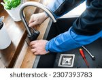 Small photo of Plumber repair water tap in kitchen, Close up of hands of repairman in blue uniform fixing leaking water, broken kitchen tap using adjustable wrench. Repair service concept.