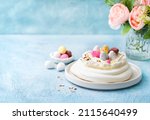 Small photo of Easter cake Meringue nest cake Pavlova with colorful chocolate eggs, buttercream frosting, light blue background with copy space. Selective focus. Close up. Easter Spring love feast concept.