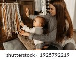 Small photo of mom and daughter home atmosphere. Snuggery. Baby reaches for macrame