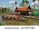Small photo of Ayutthaya, Thailand - December 22, 2010: Boatmen fore and aft guiding a wooden touring boat along a klong (canal) at the Ayutthaya Floating Market