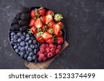  Strawberries, raspberries, blueberries, blackberries on a separate dish close-up on a solid concrete background. Healthy eating Vegan food. View from above                              