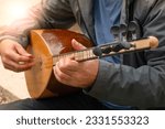 Small photo of Man playing Turkish musical instrument baglama which is the most commonly used string folk instrument in Turkey