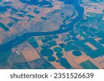 Small photo of Aerial view of center-pivot irrigation in which equipment rotates around a pivot and crops are watered with sprinklers with river in Europe.