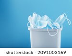 Waste bin full of used protective masks on a light blue background with free space. Throw away the Used Mask