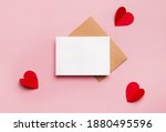 Mockup blank greeting card for valentines day. Composition with red hearts for Valentine's Day on a pale pink background. Flat lay. Love and relationships concept.