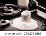 Small photo of whey or white casein, athletes food supplement, with dumbbells and bodybuilding weight on black background