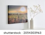 Small photo of Canvas photo print with gallery wrap and flowers in vase, interior decor. Landscape photography hanging on white wall