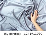 Female hand touching smooth elegant silk or satin luxury cloth texture