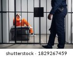 Small photo of A prison guard makes a tour of the cells in a high-security prison. The cells are occupied by criminals in red robes