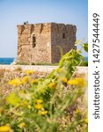 Small photo of Baroque watchtower, beautiful old tower in San Vito, Polignano a Mare, Bari, Puglia, Italy with with blue sea, stone wall and flowers, Mediterranean landscape