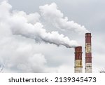 Thick white smoke from industrial factory old rusty chimneys on a cloudy grey sky background