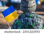 Child or kid with winter clothes, hat and Ukrainian flag, profile of the child is on the flag. War in Ukraine, caused by Putin and Russian aggression, refugee, refugees camp