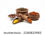 Spices in wooden bowls and spoons, pepper mixture in glass bowl isolated on white background.