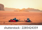 Two caucasian lovers couple watch sunset hold hands in wadi rum desert on holiday vacation abroad share memories experiences travel together while young on sunset over horizon