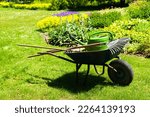 Small photo of A gardeners wheelbarrow with the gardening tools in the gardens. Gardening concept