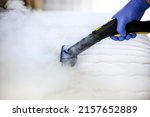 Cleaning and disinfection of the mattress in the bedroom with hot steam. Professional cleaning process