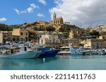 Small photo of Mgarr, Gozo - September 13th 2022: Fishing boats and the AFM search and rescue launch Melita II moored in Mgarr Harbour overlooked by the Church of Our Lady of Lourdes.