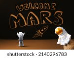 Figures of astronauts on the background of a chalky black board with the inscription welcome to Mars and a flying rocket. Mars colonization.