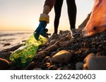 Conservation of ecology and garbage collection for recycling. A volunteer collects plastic bottles by the sea. Concept of coastal cleanup and global environmental pollution.