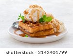 ice cream with waffles, caramel syrup and fresh mint on a white dish